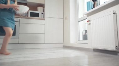 Çocuk, yapışkan filmle kaplamak için hamurlu bir tabak taşıyor..