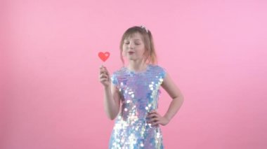 Mutlu kız, elinde bükük elbiseler, kalp şeklinde bir çubuğun üzerinde şeker.