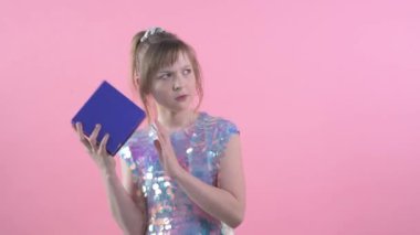 Güzel, parlak elbisesi olan meraklı kız, hediyesiyle bir kutuyu sallıyor..