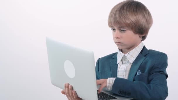 El chico lindo escribiendo en su computadora portátil y quitándose con la mano en la cara — Vídeos de Stock