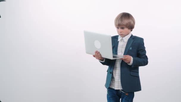 Cute upset boy holding a laptop. The child is not happy. — Stock Video
