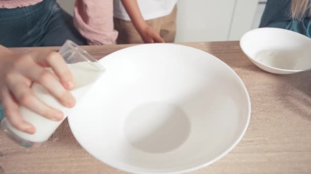 Primer plano de hacer masa, verter la leche en el plato. Los niños ayudan a mamá con la cocción — Vídeo de stock