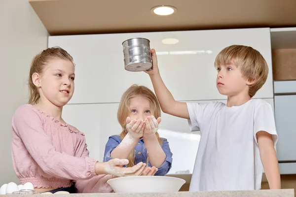 Kinder bereiten für Mama eine Überraschung vor und backen Teig, Leberkuchen. — Stockfoto