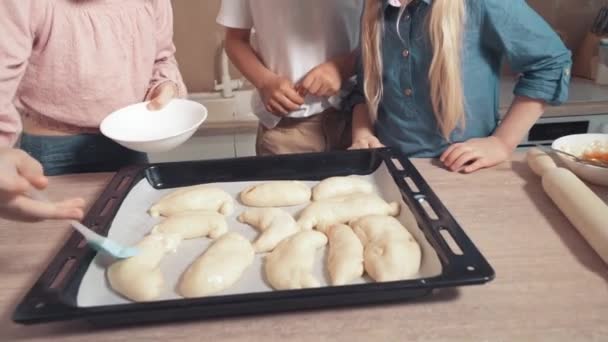 Kinder backen Gebäck und schmieren den Teig mit einer Silikonbürste. — Stockvideo