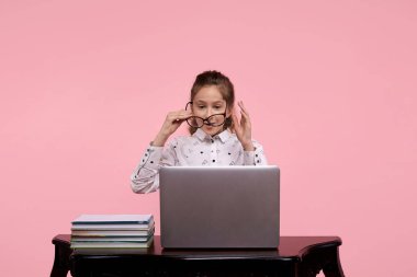 Siyah çerçeveli bir kız. Bilgisayarı ve kitapları olan bir kız masada oturuyor..