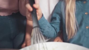 Çocuklar mutfakta yemek pişirmeye yardım eder. Hamuruna süzgeçten un ekle.