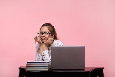 Beyaz bluzlu ve kot pantolonlu bir kız kafasını büyük gözlüklerle destekliyor.