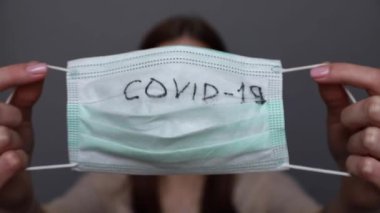 Kadın, Covid19 ve Coronavirus 'u korumak için cerrahi maske gösteriyor.