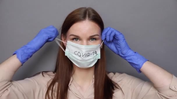 Женщина снимает хирургическую маску для защиты Ковид-19, коронавируса — стоковое видео