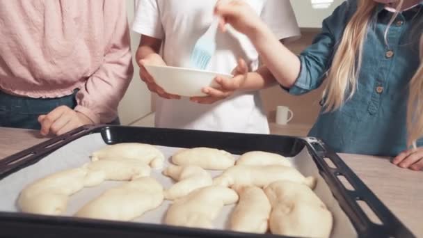 Les enfants cuisinent des pâtisseries et enduisent la pâte avec une brosse en silicone . — Video