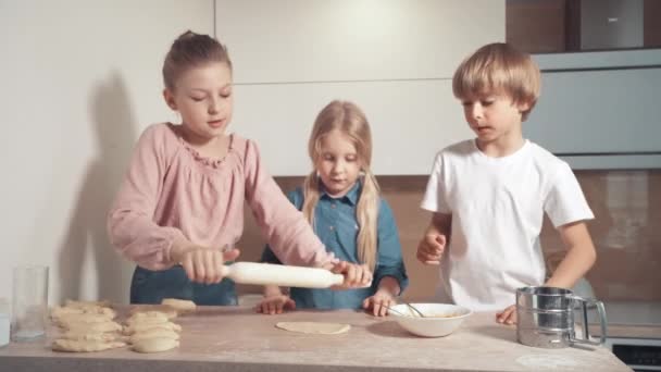 Niedliche blonde Kinder bereiten Plätzchen mit Füllung in der Küche zu. — Stockvideo