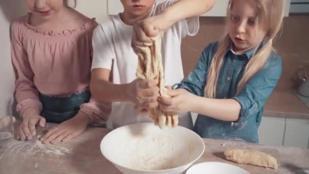 Leuke kinderen, een jongen en een blond meisje, bereiden een koekjesdeeg — Stockvideo