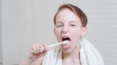 Dilini diş fırçası ve jöle ile fırçalayan tatlı esmer çocuk. Parlak banyo.