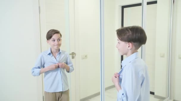 The boy zips up his blue shirt and looks in the mirror. — Stock Video
