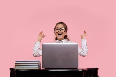 Güzel bir kız şaşırdı ve kollarını açtı. Dizüstü bilgisayarı ve kitapları olan masa..