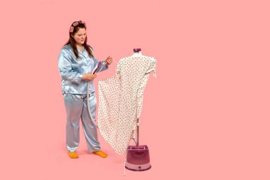 Güzel, dolgun bir kız onu buharlaştırmak için elbise asıyor. Pijamalı kız..