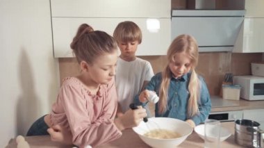 Çocuklar pasta ve kurabiye için hamur hazırlar. Hamuruna tuz ekle. Bir çırpıcıyla karıştır