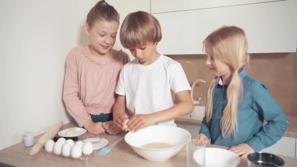 Carino bei bambini biondi stanno cucinando pasta insieme. Sbattere le uova nel piatto . — Video Stock