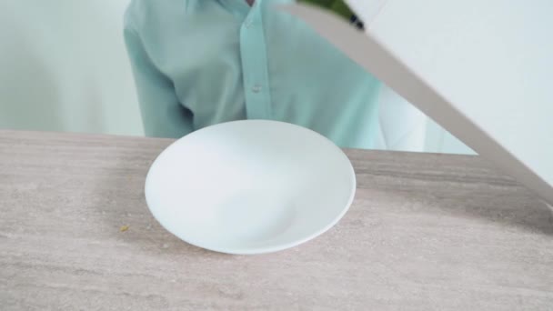 A man sprinkles cornflakes in a white plate. Proper nutrition. — Stock Video