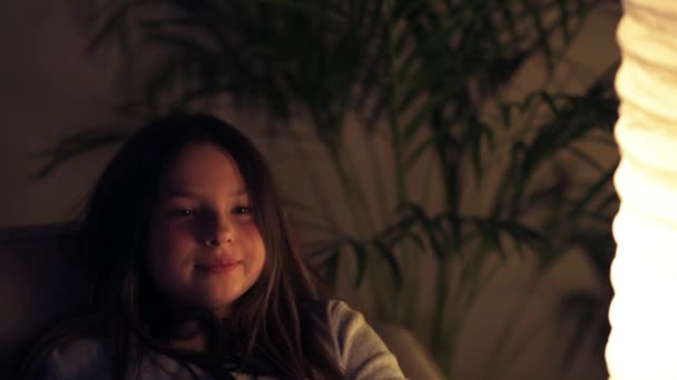 Vacker liten flicka som tittar på TV hemma på natten. Hemskt i filmen. — Stockvideo