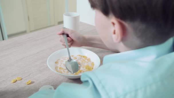 Brunetka chłopiec je śniadanie pyszne słodkie płatki kukurydziane z mlekiem. — Wideo stockowe