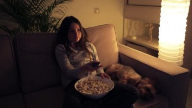 Güzel bir kız uzaktan kumandayla kanal değiştirir.