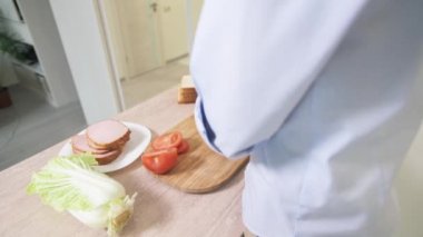 Ekmek ve jambondan sandviç yapan bir çocuğun arkasından bir manzara.