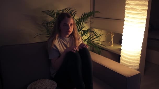 겁에 질린 한 소녀가 어둠 속에서 공포 영화를 보고 겁에 질려 돌아서는 모습. — 비디오