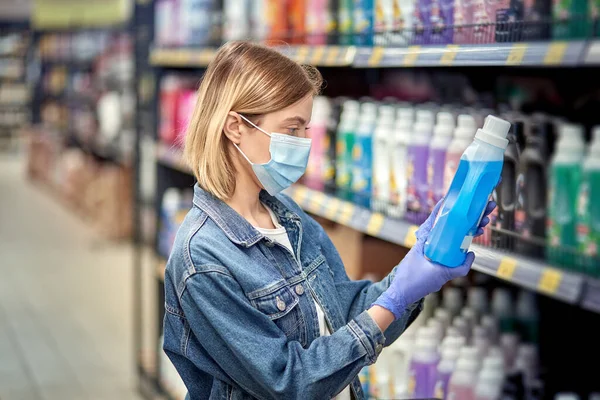 Όμορφη νεαρή κοπέλα σε ένα κατάστημα με ένα καλάθι επιλέγει οικιακά χημικά — Φωτογραφία Αρχείου