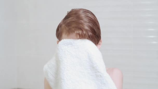 A handsome boy with a clean face and wet hair wipes his face with a towel. — Stock Video