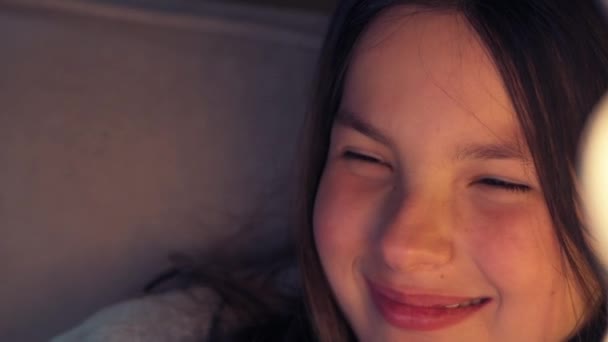 Gros plan d'une fille souriante qui regarde la télé. Noisette grands yeux. — Video