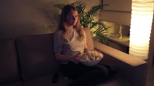 En rädd söt tjej tittar på en läskig film på TV på natten.. — Stockvideo