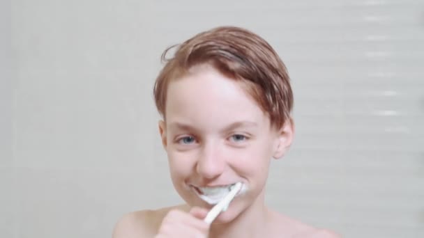 Netter lustiger Junge putzt seine Zähne und tanzt im Badezimmer neben dem Spiegel. — Stockvideo