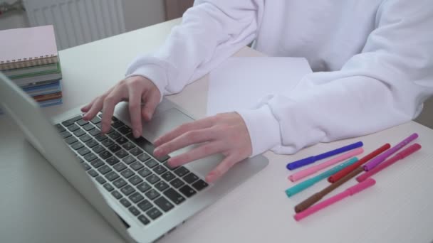 ノートパソコンに文字を入力する女の子。オンラインの授業。テーブルの上に本がある — ストック動画
