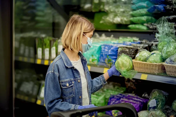 Молода дівчина стоїть в магазині і тримає в руці свіжі овочі . — стокове фото