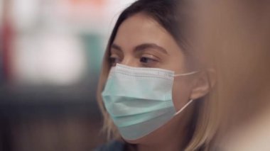 Tıbbi maskeli arkadaşıyla konuşan genç ve güzel bir kızın yakın çekimi..