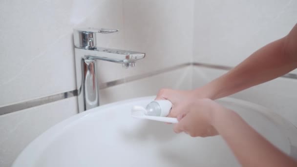 Чоловік кладе зубну пасту на зубну щітку у ванній . — стокове відео