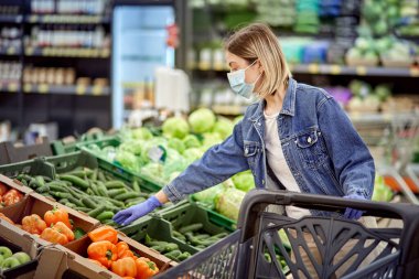 Eldivenli ve maskeli bir kız dükkandan taze yemek seçiyor. Tıbbi maskeli kız..