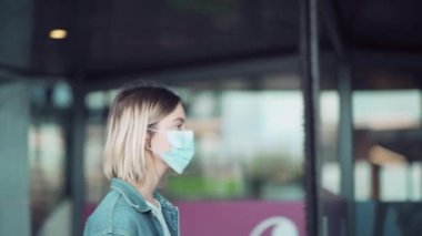Yüzü maskeli sarışın bir kız alışveriş merkezine tıbbi maske takarak gelir..