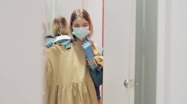 Sarışın kız aynanın yanındaki dükkandan kıyafet seçiyor. Güvenli alışveriş gezisi.