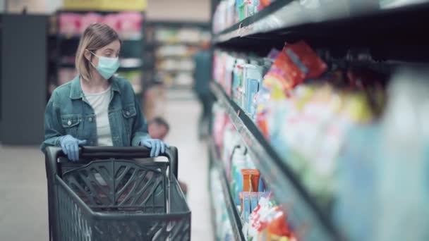 의료용 마스크를 쓴 아름다운 소녀 가 가게에서 물건을 산다. — 비디오