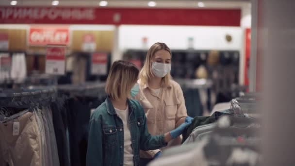 Due amici biondi fanno shopping e sorridono in maschere mediche. — Video Stock