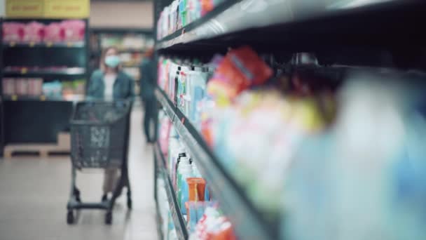 Una giovane ragazza cammina per il negozio con un carrello della spesa e seleziona la merce. — Video Stock