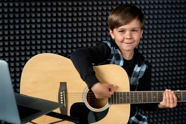 Leende brunettpojke spelar gitarr. Lär dig att spela ett musikinstrument. — Stockfoto