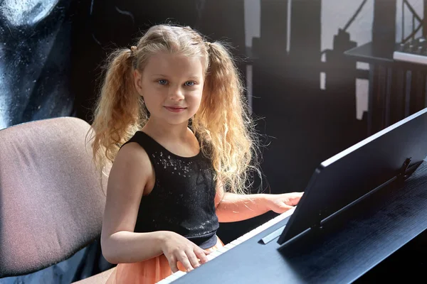 かわいい金髪の女の子がスタジオでピアノを演奏します。女の子で美しいドレス. — ストック写真