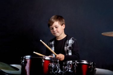Çocuk kırmızı davul çalıyor. Bir müzik aleti çalmayı öğrenmek.