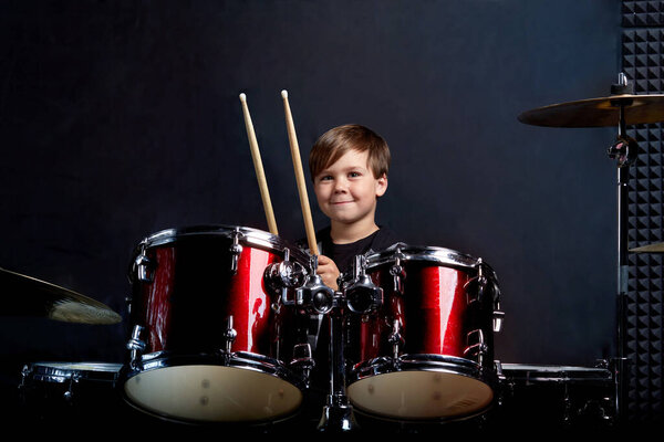Cheerful smiling child plays the drums. Boys Studios.