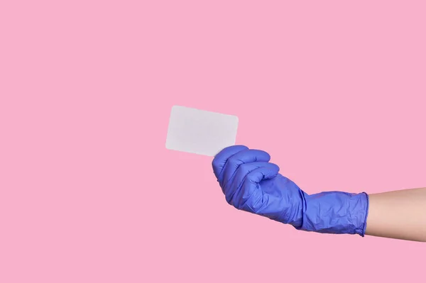 Ręka w rękawicy lateksowej posiada wizytówkę, kartę kredytową lub pusty papier izolowany — Zdjęcie stockowe