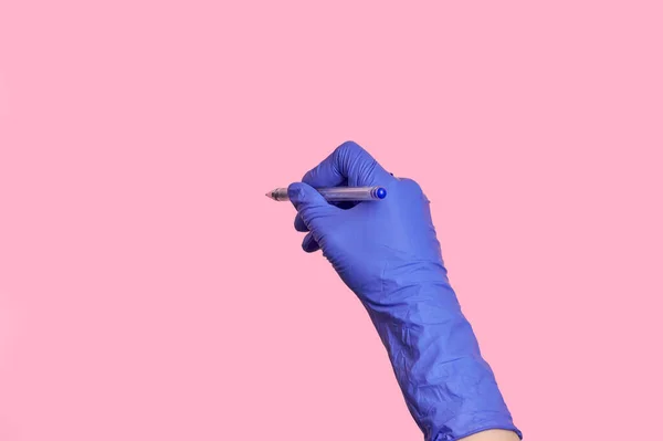 Mano de cerca en guantes de látex médico escribiendo información con una pluma . — Foto de Stock