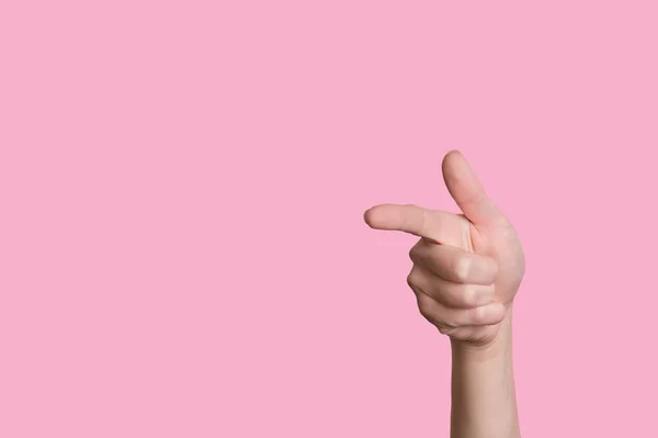A kéz egy fegyver mozdulatát mutatja, vagy balra. Izolált rózsaszín háttér. — Stock Fotó